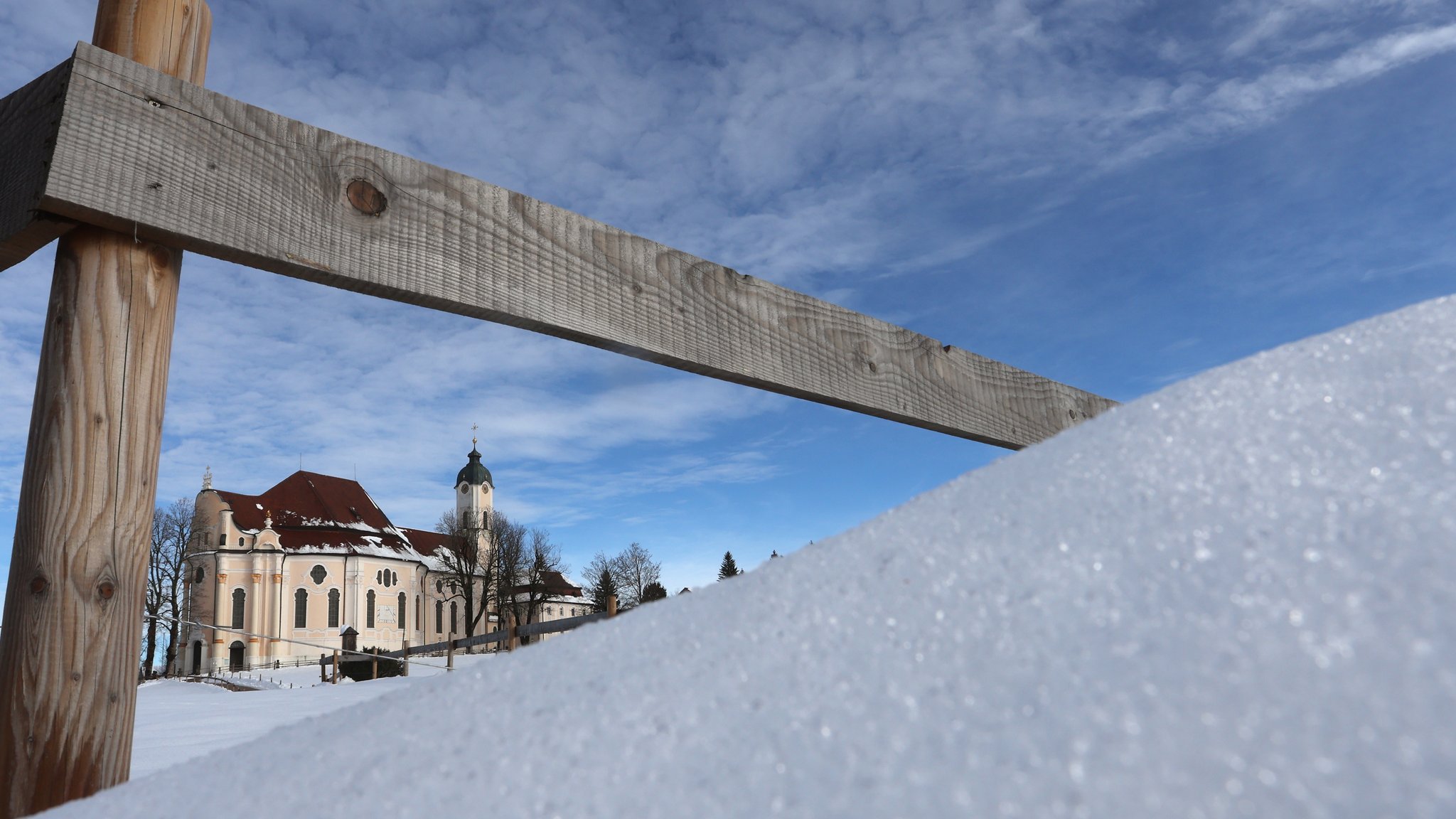 In tief verschneiter Landschaft steht die Wieskirche im Sonnenschein.