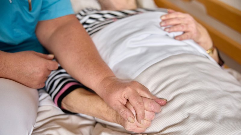 Frau hält Hände der Bewohnerin einer Palliativstation | Bild: pa/dpa/Werner Krueper Frau hält Hände der Bewohnerin einer Palliativstation