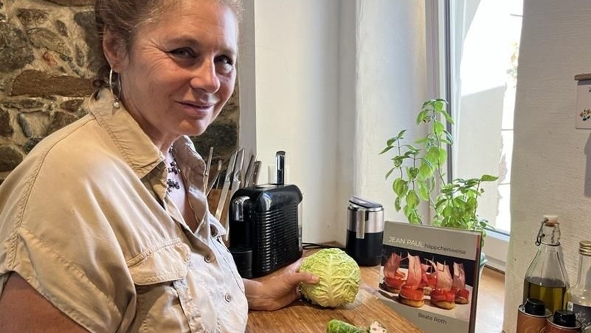 Köchin und Foodstylistin Beate Roth steht mit einem Kohlkopf in der Hand vor einem Schneidbrett in ihrer Küche.