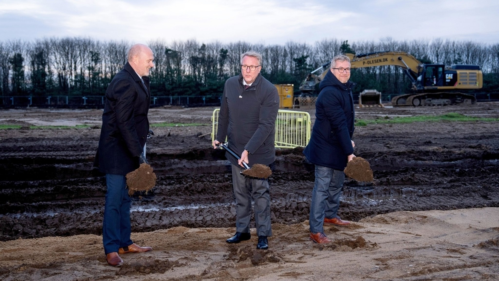 01.12.2025, Dänemark, Vojens: Der dänische Wirtschaftsminister Morten Boedskov (M), der Bürgermeister der Gemeinde Haderslev, Mads Skau (l), und der Direktor von Fire Point in Dänemark, Vyacheslav Bondarchuk, nehmen am ersten Spatenstich in der Fabrik von Fire Point in Südjütland nahe der deutschen Grenze teil. 
