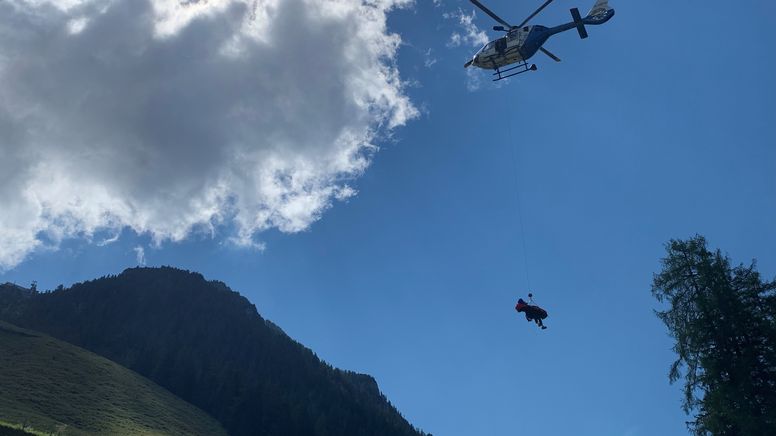 Ein Hubschrauber transportiert einen Bergretter und einen Verletzten. | Bild:Theresa Momsen / BR