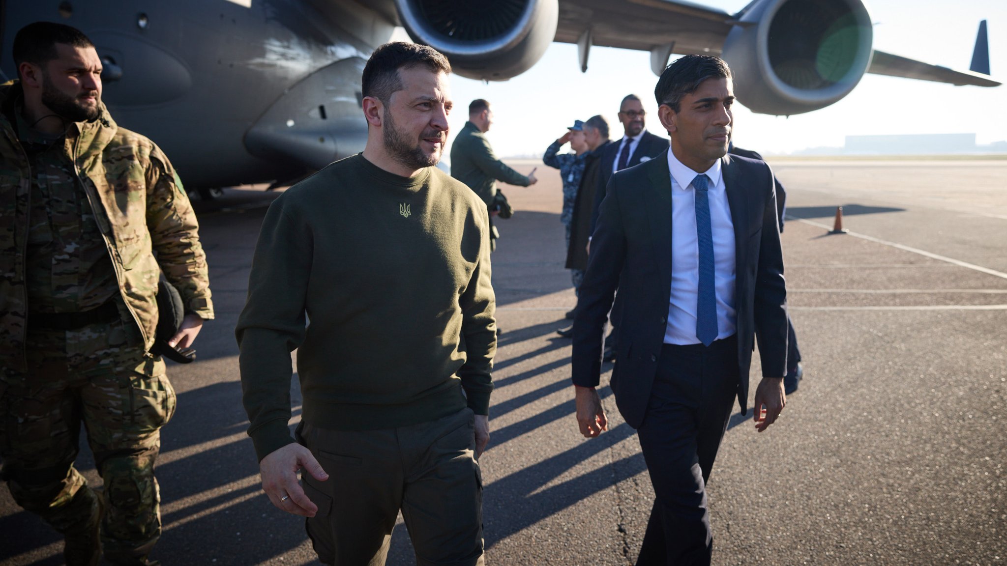 Der ukrainische Präsident Wolodymyr Selenskyj (M.) und Großbritanniens Premierminister Rishi Sunak auf dem Flughafen in London am 08.02.23.