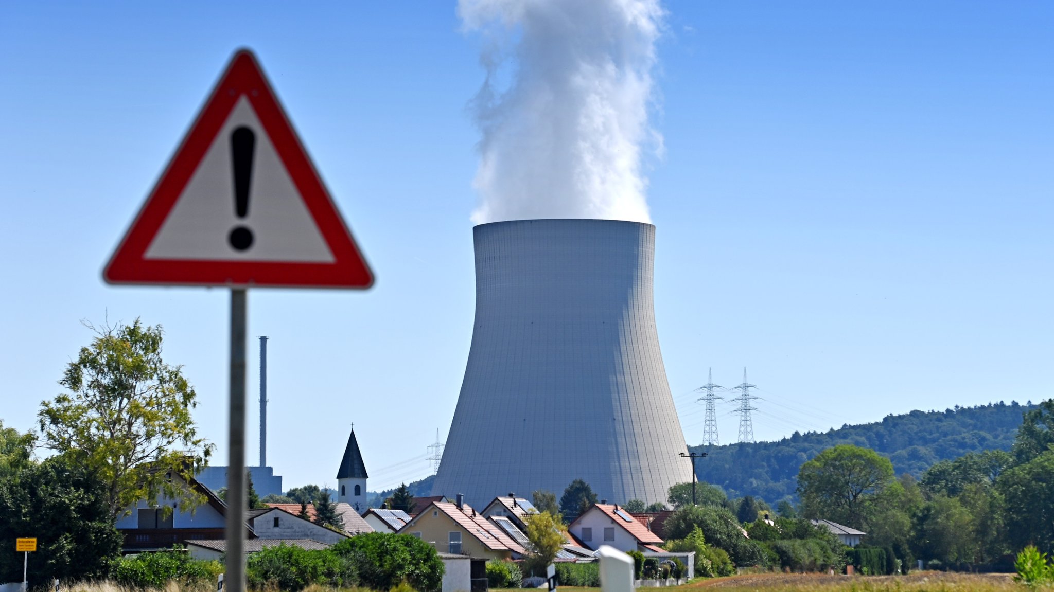 Der Kühlturm des Kernkraftwerks Isar 2, im Vordergrund ein Verkehrsschild mit Ausrufezeichen