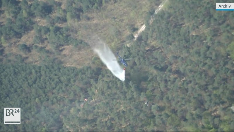 Hubschrauber löscht Waldbrand aus der Luft.