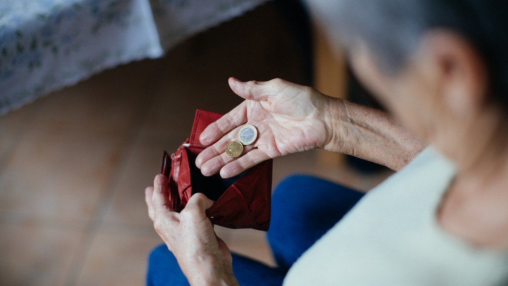 Eine Seniorin mit einem Geldbeutel in der Hand
