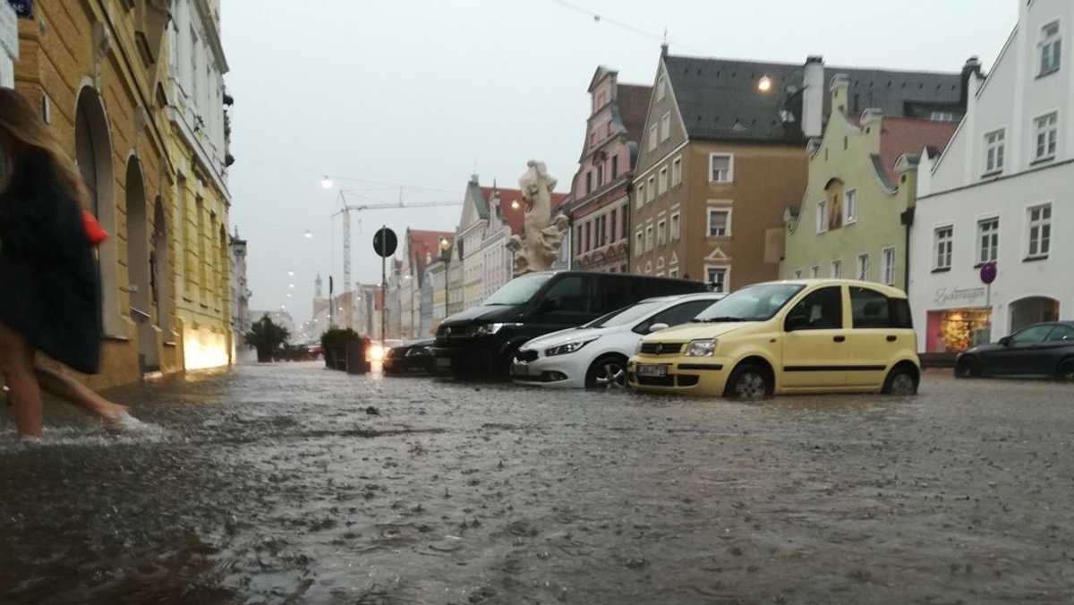 Eine Frau geht barfuß durch das Wasser in der Innenstadt in ein Haus. Außergewöhnliche Regenmassen hatten die Altstadt am 29.6. unter Wasser gesetzt.