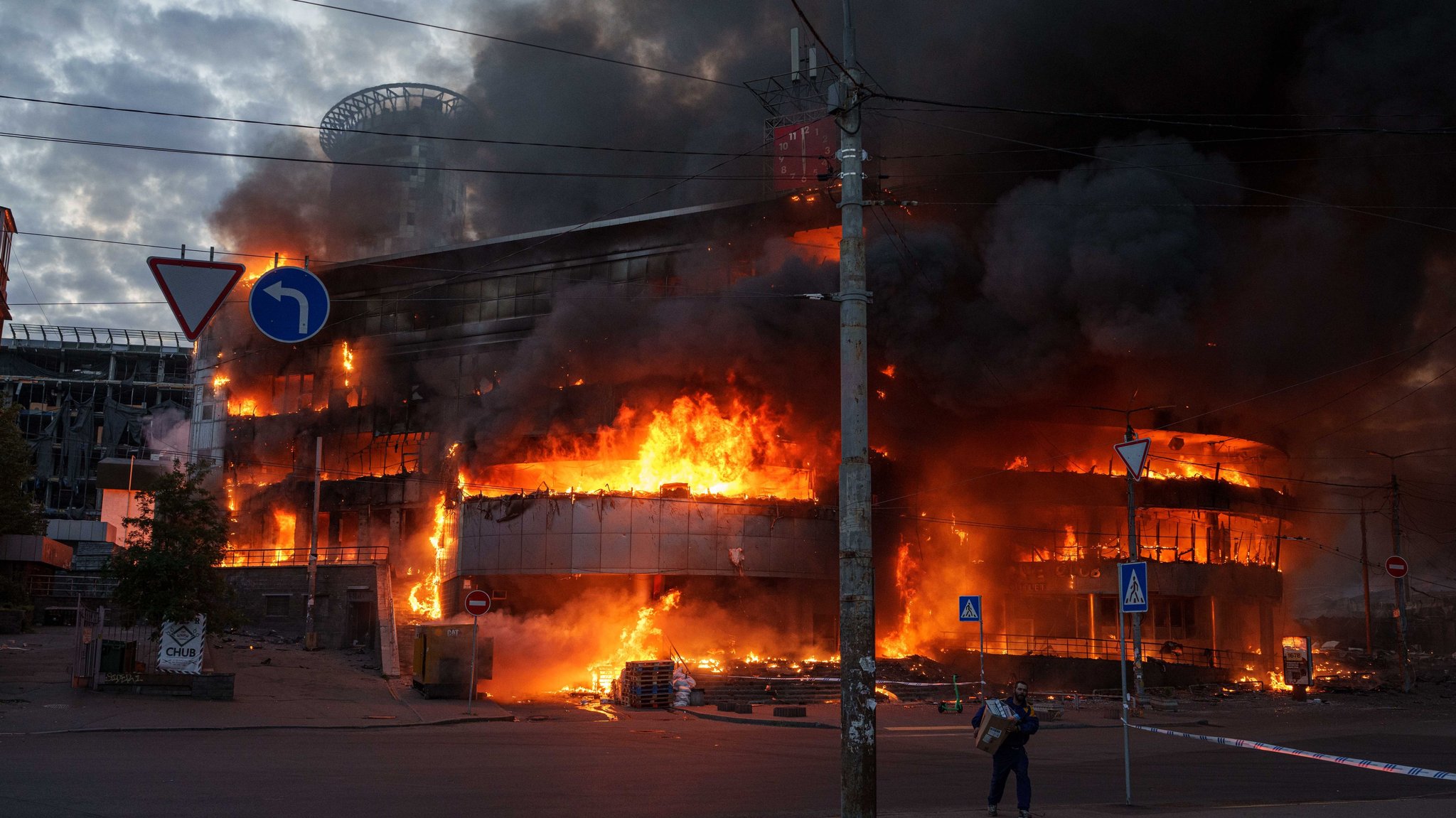 dpatopbilder - 24.05.2026, Ukraine, Kiew: Ein Mann trägt eine Kiste aus einem brennenden Handelszentrum nach einem russischen Angriff auf Kiew. Foto: Evgeniy Maloletka/AP/dpa +++ dpa-Bildfunk +++ | Bild: dpa-Bildfunk/Evgeniy Maloletka dpatopbilder - 24.05.2026, Ukraine, Kiew: Ein Mann trägt eine Kiste aus einem brennenden Handelszentrum nach einem russischen Angriff auf Kiew. Foto: Evgeniy Maloletka/AP/dpa +++ dpa-Bildfunk +++