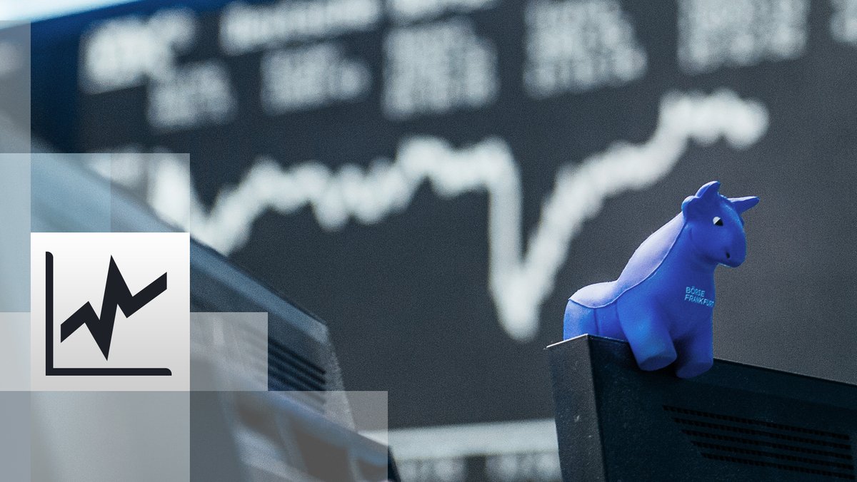  ein blauer Stier aus Gummi sitzt auf der oberen Kante eines Bildschirmes, im Hintergrund die Kurstafel der Börse