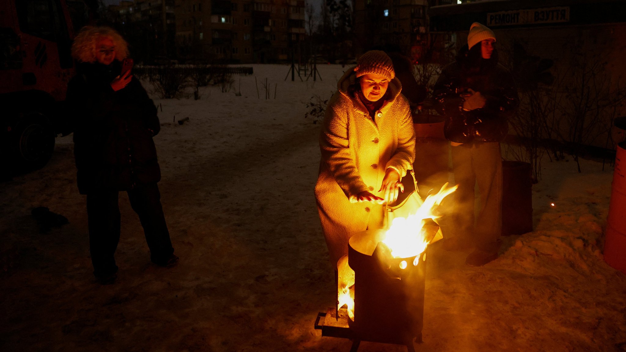Frauen wärmen sich während eines Blackouts in Kiew an einem Feuer auf