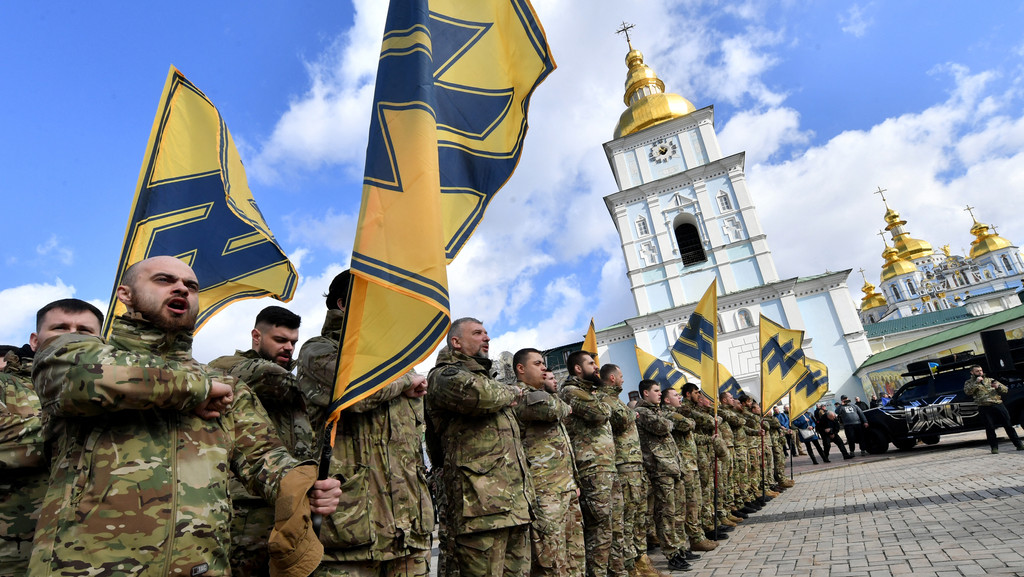 Asow-Veteranen halten Flaggen mit der Wolfsangel hoch bei einer Demonstration mit dem Titel “Keine Kapitulation” im März 2020 in Kiew. Fünfzehntausend Menschen kamen damals zusammen trotz des Verbots von Massenevents wegen des Coronavirus, und forderten den Rücktritt von Präsident Selenskyj.