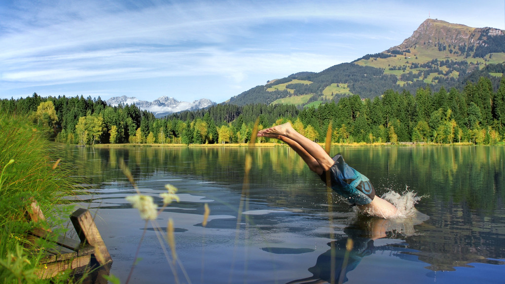 Ein Mann springt mit einem Kopfsprung in einen See.