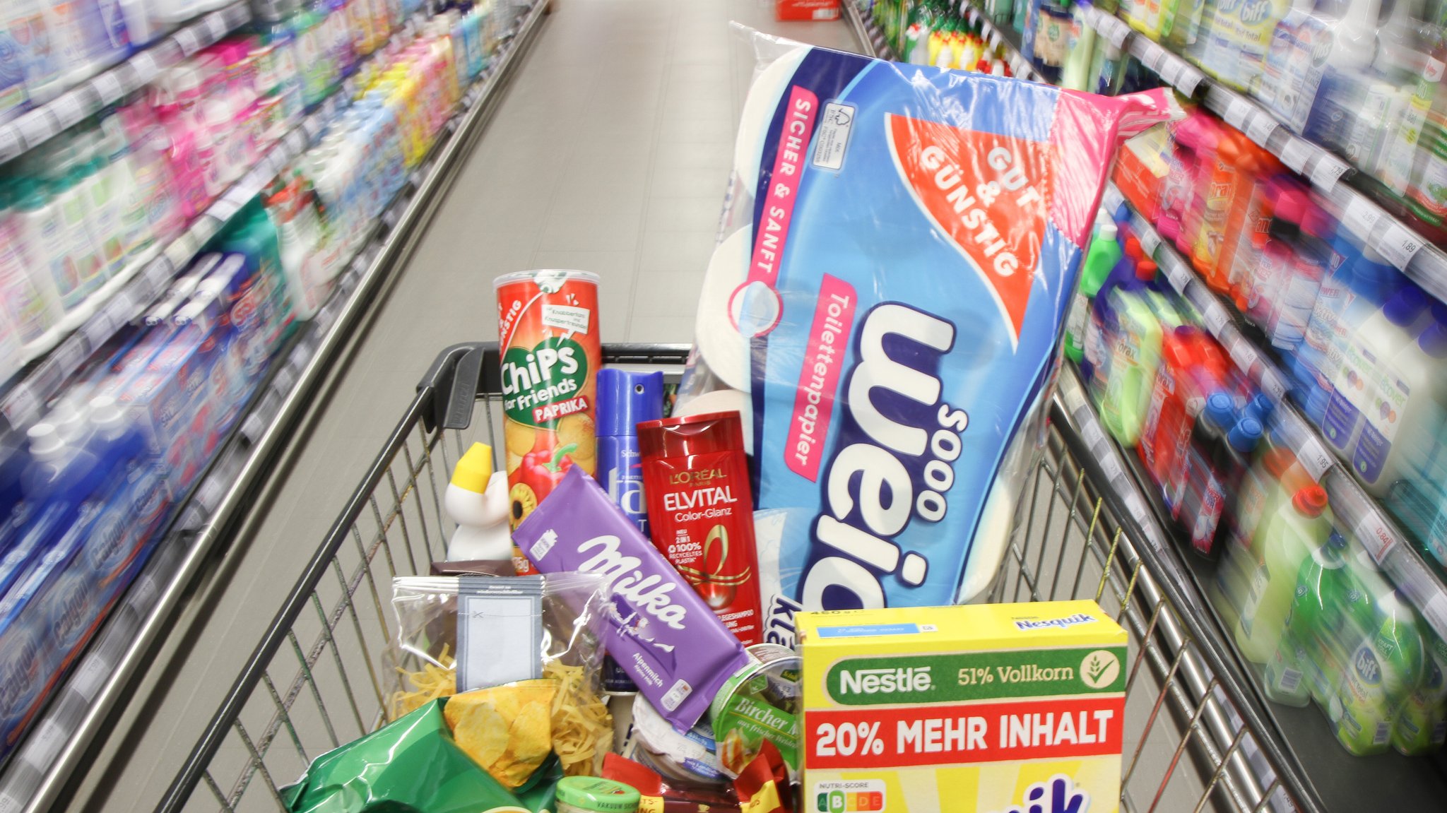 Ein vollbeladener Einkaufswagen mit Produkten fährt durch die Gänge in einem Discounter. (Symbolbild)