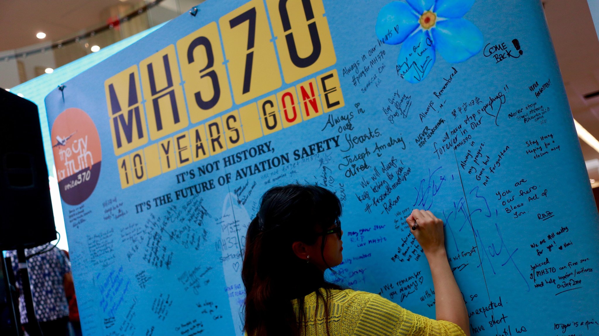 Frau schreibt an Erinnerungstafel für Verschollene von Flug MH370, März 2024