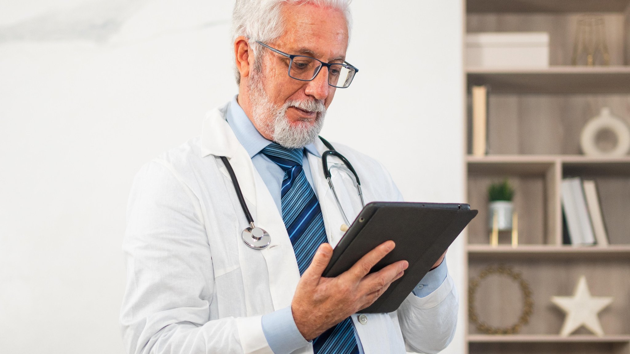 Älterer Arzt schaut auf ein Tablet | Bild: picture alliance / Iuliia Zavalishina Älterer Arzt schaut auf ein Tablet