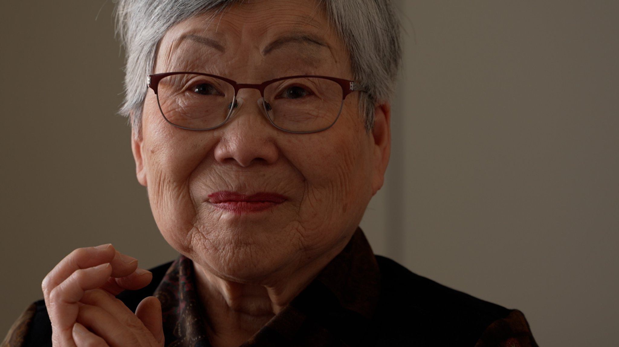 Katsuko Yabuki-Schmid schaut in die Kamera, ihre Lippen zusammengepresst, der Blick voll Kummer