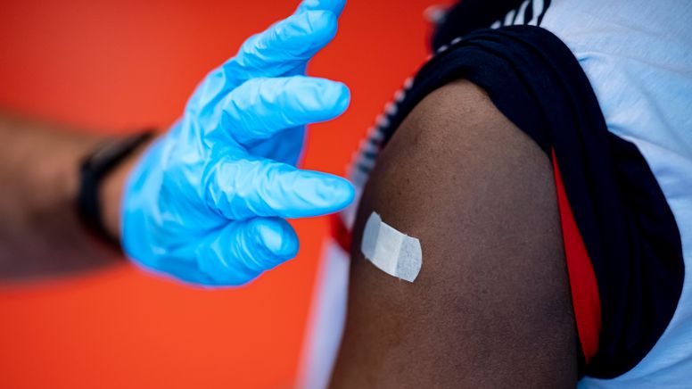 Ein Impfarzt klebt nach der Impfung ein Pflaster auf den Arm der Geimpften. | Bild:picture alliance/dpa | Fabian Sommer