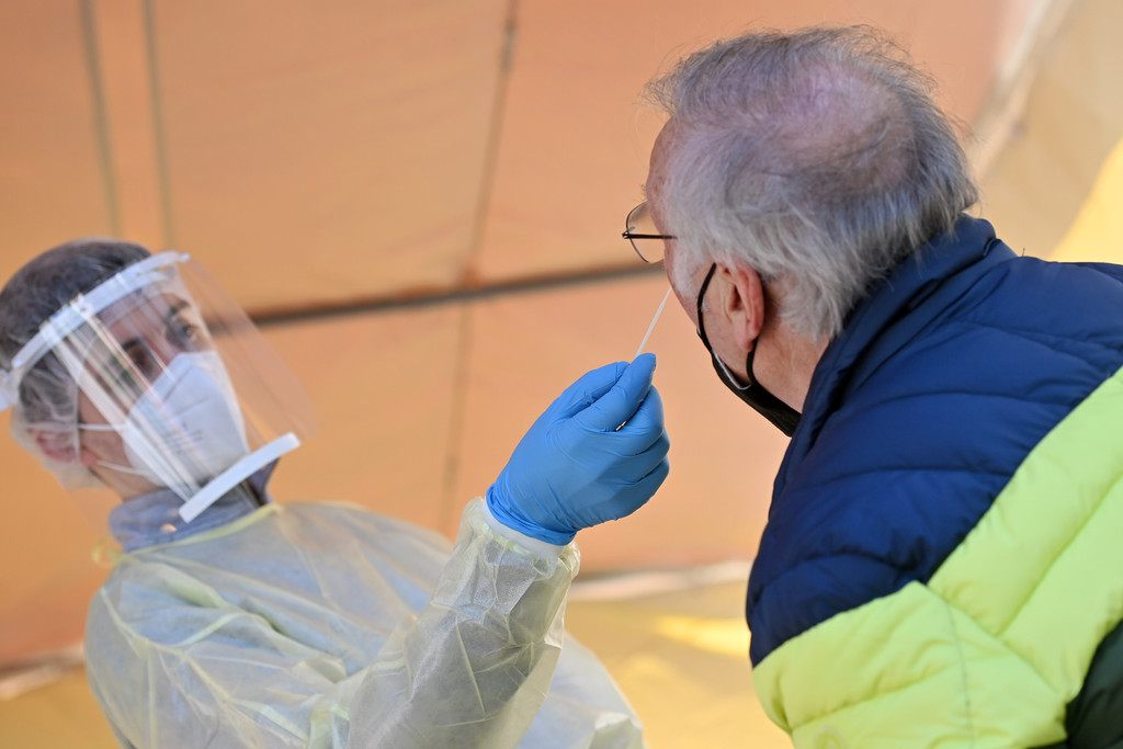 Ein Mitarbeiter eines Testzentrums nimmt bei einem älteren Mann einen Nasenabstrich für einen Corona-Test.