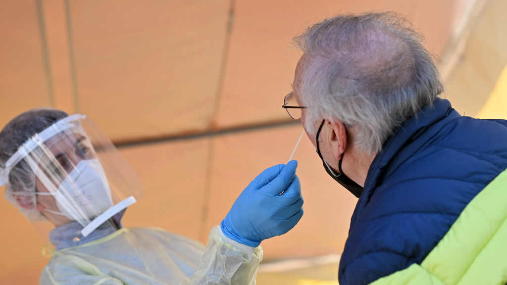 Ein Mitarbeiter eines Testzentrums nimmt bei einem älteren Mann einen Nasenabstrich für einen Corona-Test.