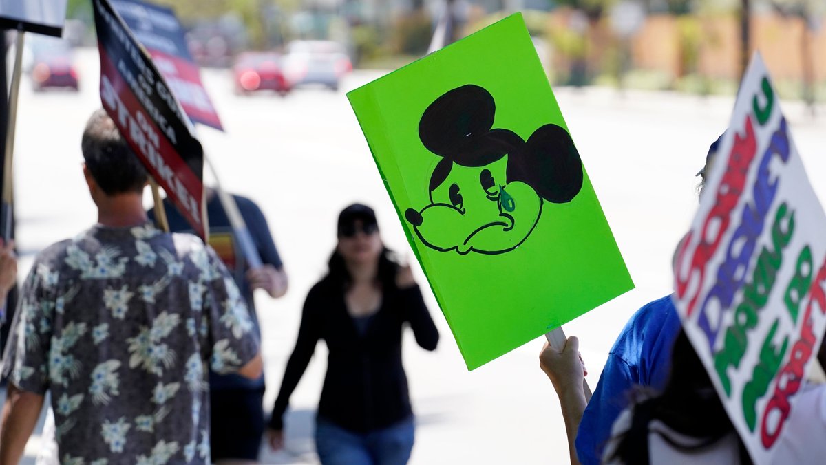 Ein Teilnehmer der Writers Guild-Kundgebung am 17.05.2023 mit einem Schild, auf dem eine weinende Mickey Maus abgebildet ist, vor dem Studio der Walt Disney Company.