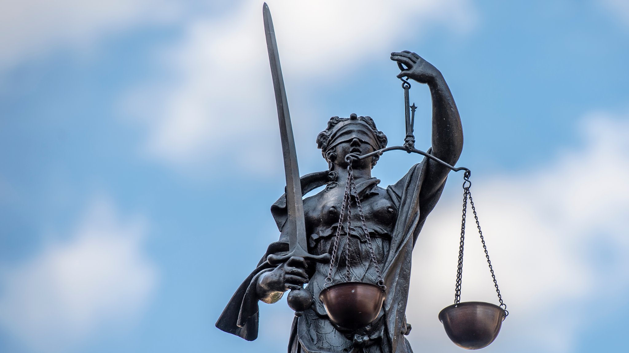 Justitia mit verbundenen Augen vor blauem Himmel (Symbolbild)