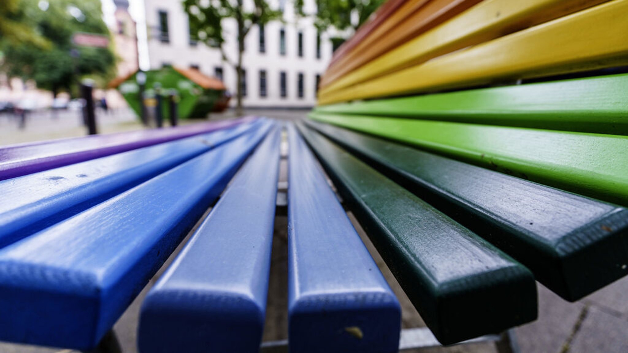 (Symbolbild) Eine Bank, deren Latten in Regenbogenfarben lackiert ist. 