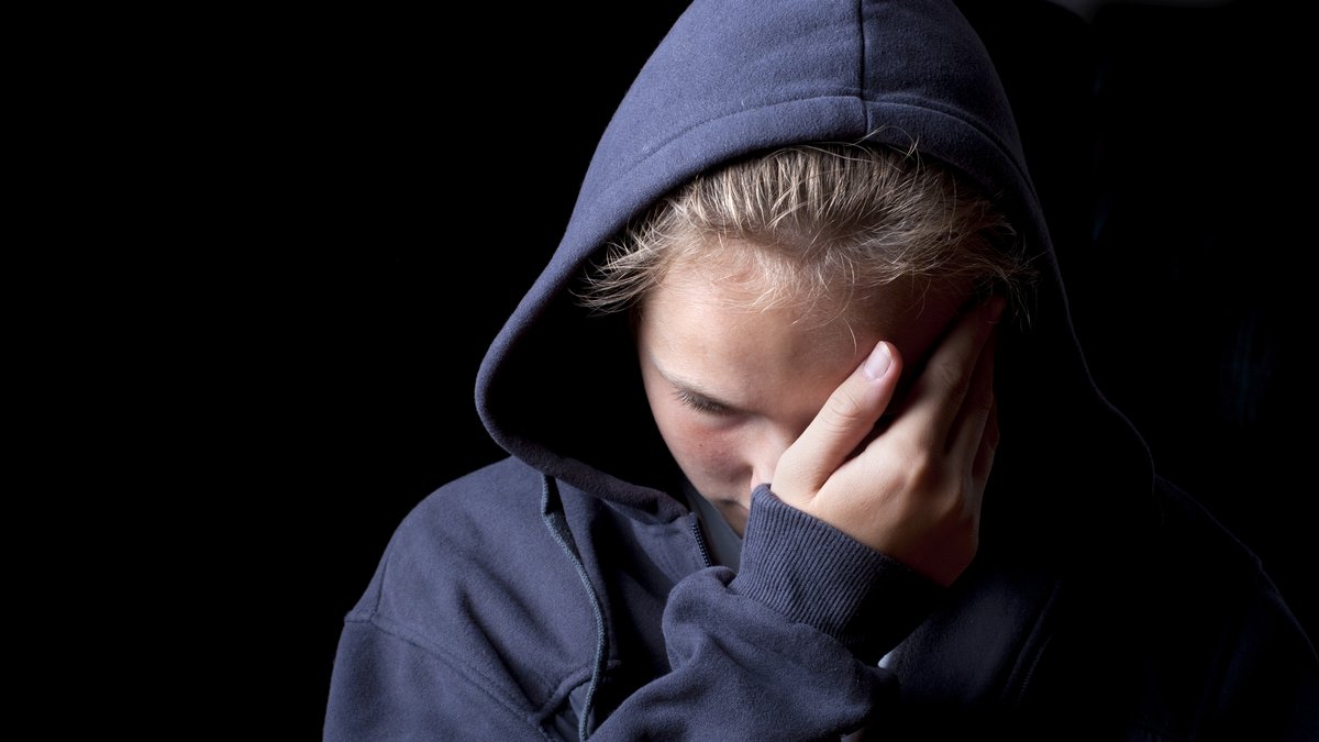 Eine traurige Jugendliche im blauen Hoodie.