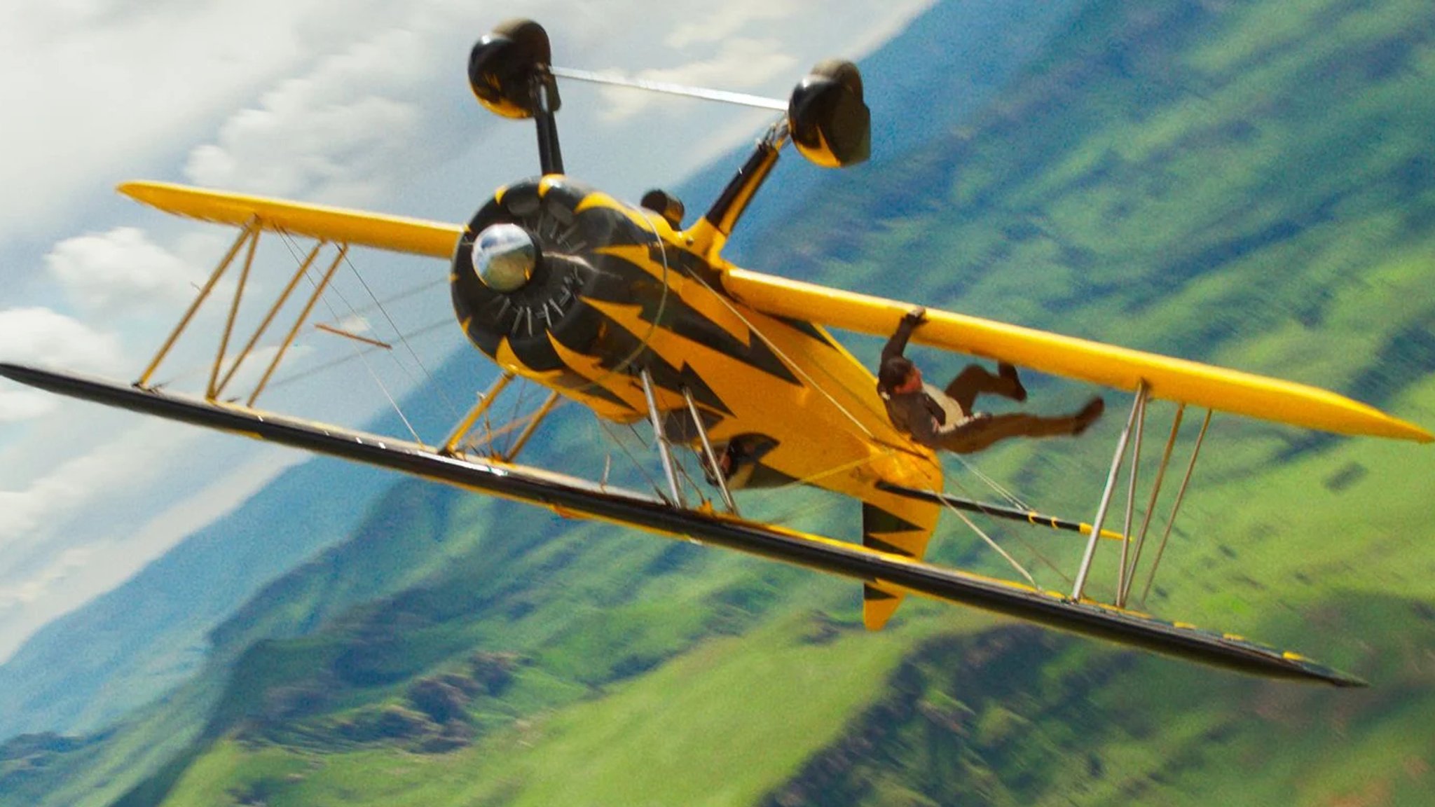 Tom Cruise als Ethan Hunt bei einer Stunt-Szene auf dem Flügel eines Doppeldecker-Flugzeugs, das gerade kopfüber fliegt (Szene aus "Mission Impossible 8 – The Final Reckoning")
