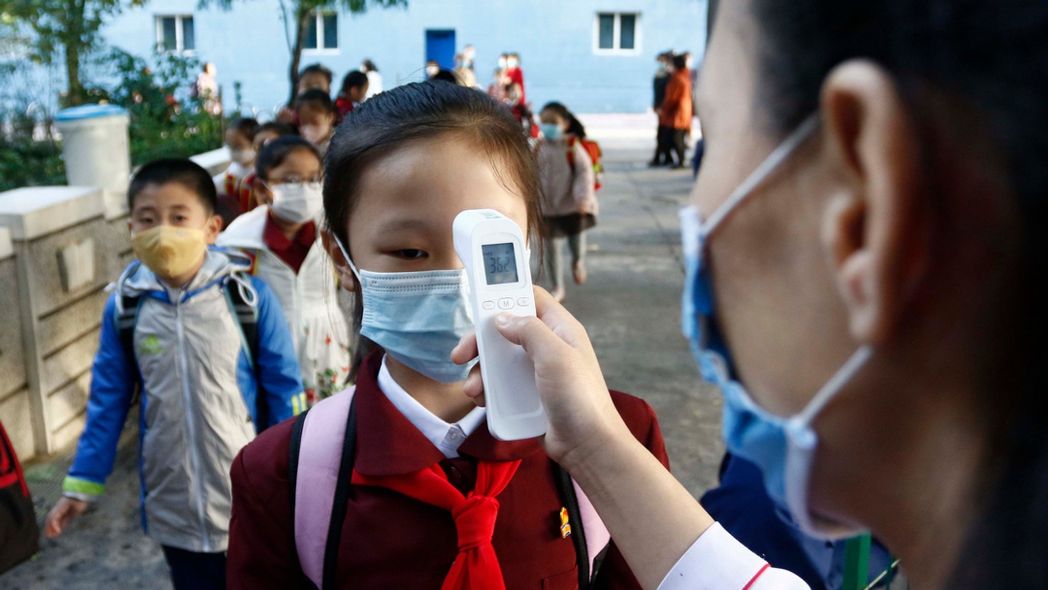 Archivbild (Oktober 2021): Pjöngjang: Eine Lehrerin misst die Körpertemperatur einer Schülerin, bevor sie die Kim-Song-Ju-Grundschule betritt. 