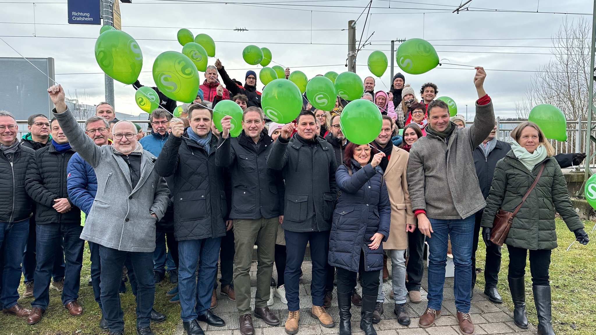 Menschen halten grüne Luftballons in die Luft