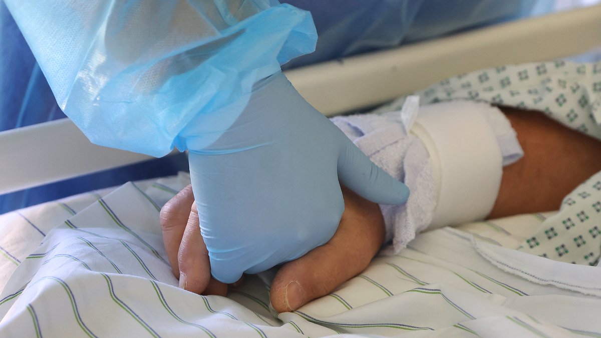 Ein Arzt hält die Hand eines Covid-19-Patienten im Klinikum Magdeburg.
