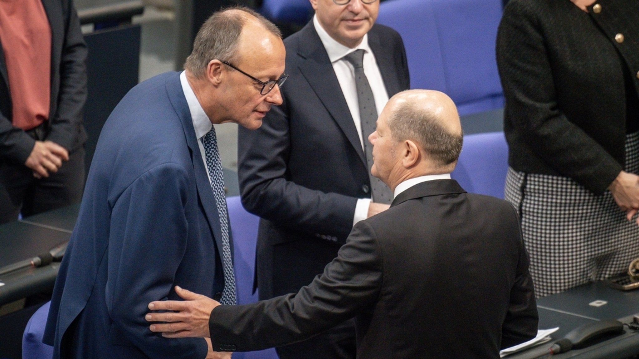 Bundeskanzler Olaf Scholz (r., SPD) spricht mit Friedrich Merz, CDU-Bundesvorsitzender, im Bundestag vor der Generaldebatte der Haushaltswoche