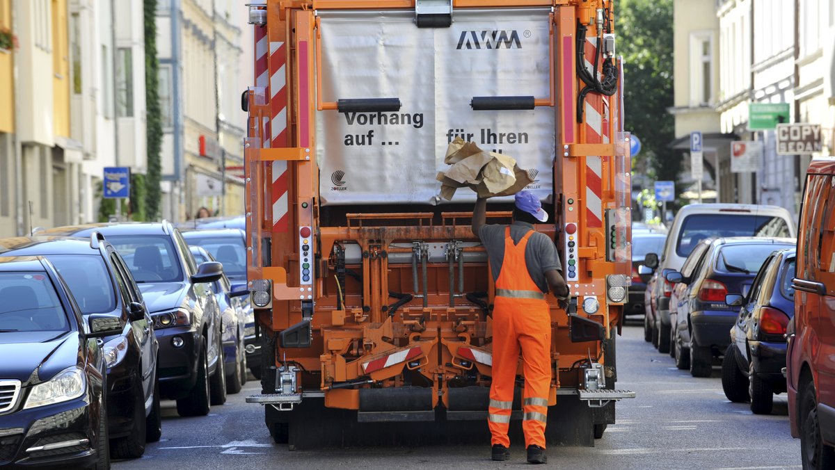 Müllwagen mit Müllmann bei der Müllentsorgung in München.