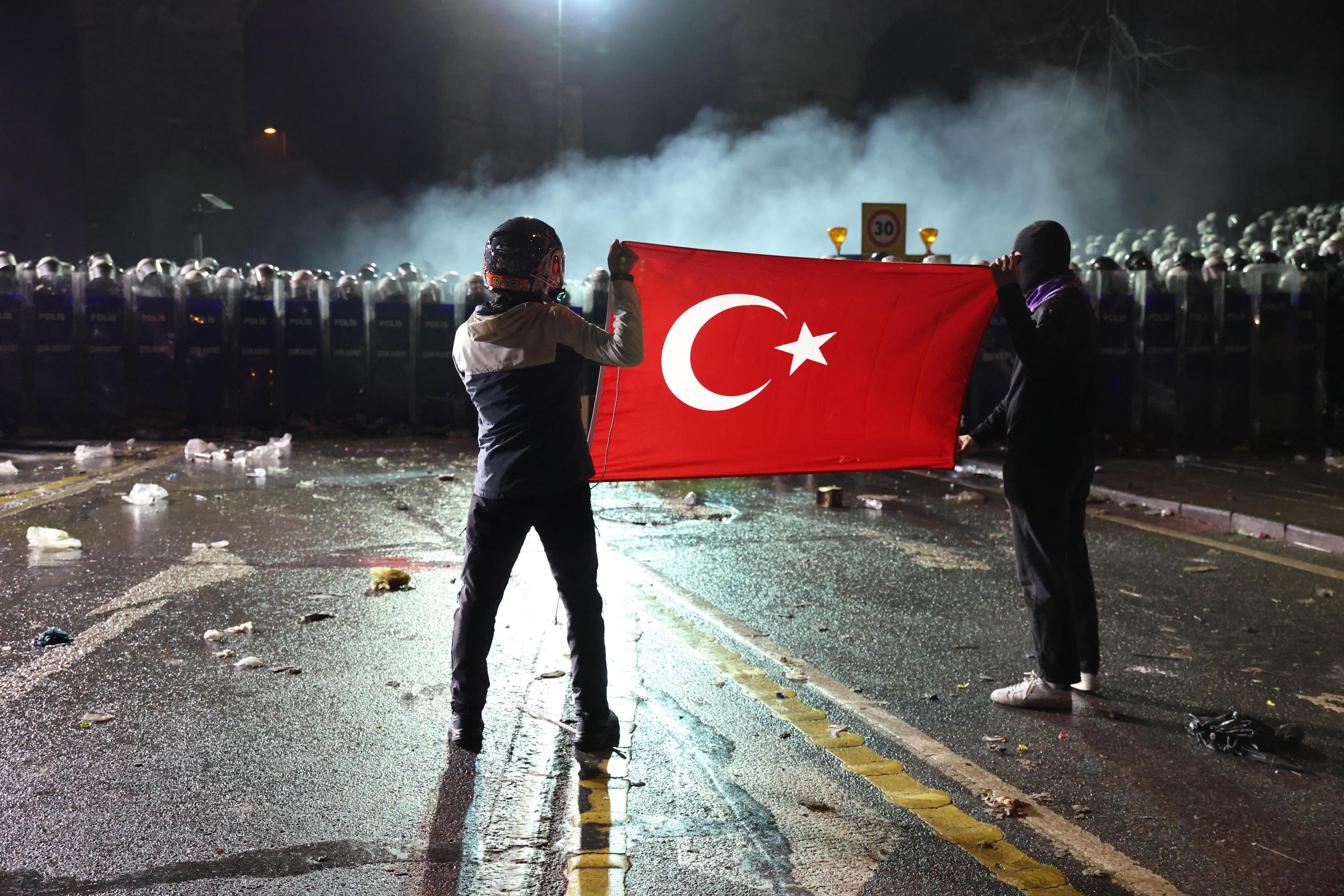 Demonstranten mit einer türkischen Flagge stehen Polizisten gegenüber.