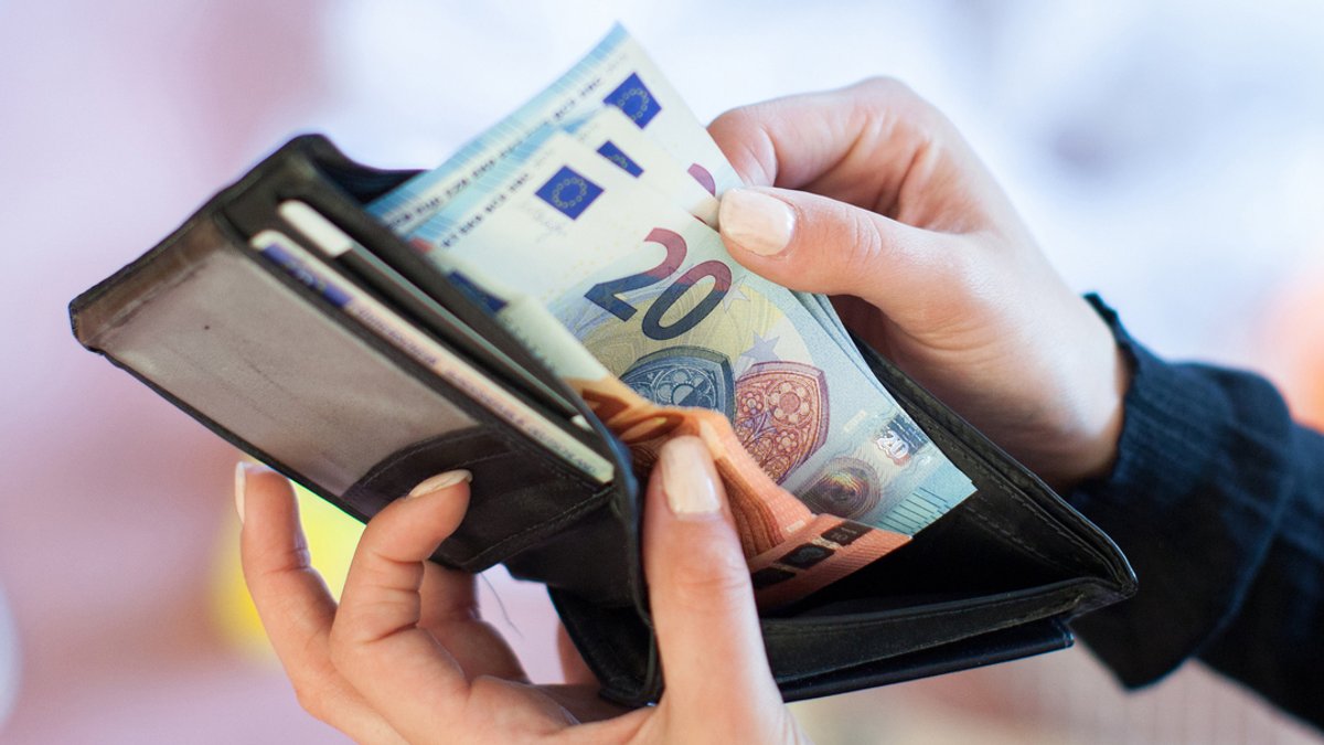 Eine Frau nimmt 20-Euro-Scheine aus einem Geldbeutel.