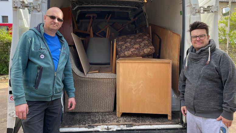 Zwei Männern vor Möbeln in einem Kasdtenwagen. | Bild:BR/Tanja Gorges