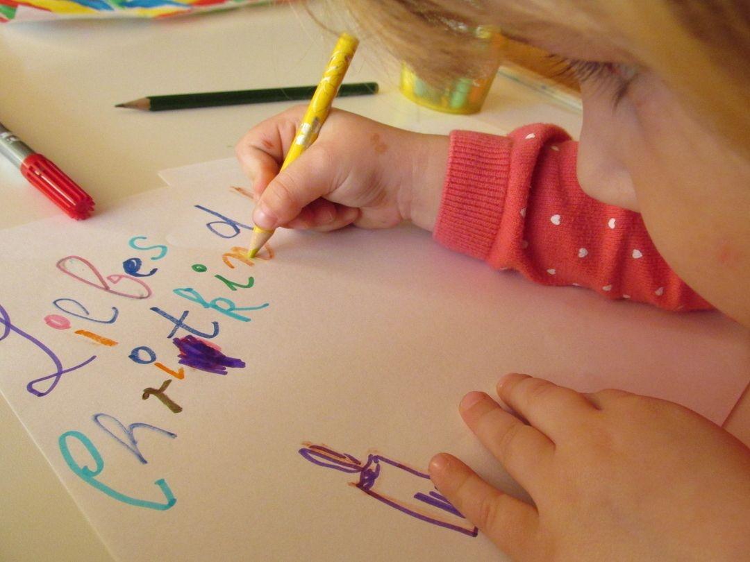 Ein Kind schreibt einen Wunschzettel ans Christkind. 