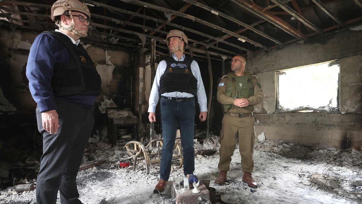 Florian Herrmann (l.), Chef der bayerischen Staatskanzlei, Markus Söder (M.), bayerischer Ministerpräsident, und Arye Shalicar, Pressesprecher der israelischen Armee, stehen im Kibbuz Nir Oz in einem zerstörten Haus.