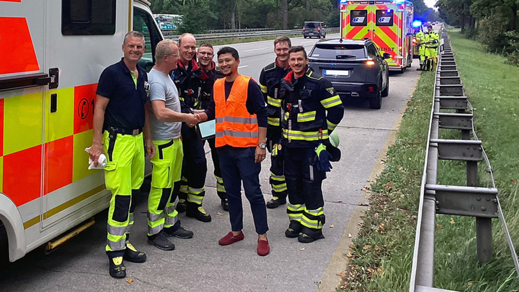 3.09.2025, Bayern, München: Die Besatzung des Einsatzfahrzeuges der Feuerwehr und der Vater eines neugeborenen Kindes (M) stehen am Einsatzort an der Autobahn. Weil es ihre Tochter eilig hatte, sind zwei Münchner auf der Autobahn Eltern geworden. Das Kind kam auf dem Weg in die Klinik zur Welt, wie die Feuerwehr mitteilt. | Bild: dpa-Bildfunk/- 3.09.2025, Bayern, München: Die Besatzung des Einsatzfahrzeuges der Feuerwehr und der Vater eines neugeborenen Kindes (M) stehen am Einsatzort an der Autobahn. Weil es ihre Tochter eilig hatte, sind zwei Münchner auf der Autobahn Eltern geworden. Das Kind kam auf dem Weg in die Klinik zur Welt, wie die Feuerwehr mitteilt.