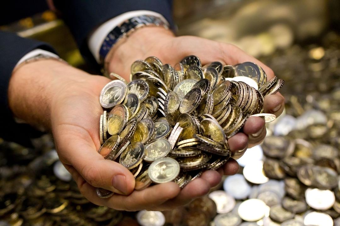 Ein Mann greift mit beiden Händen in einen Hafen Euromünzen