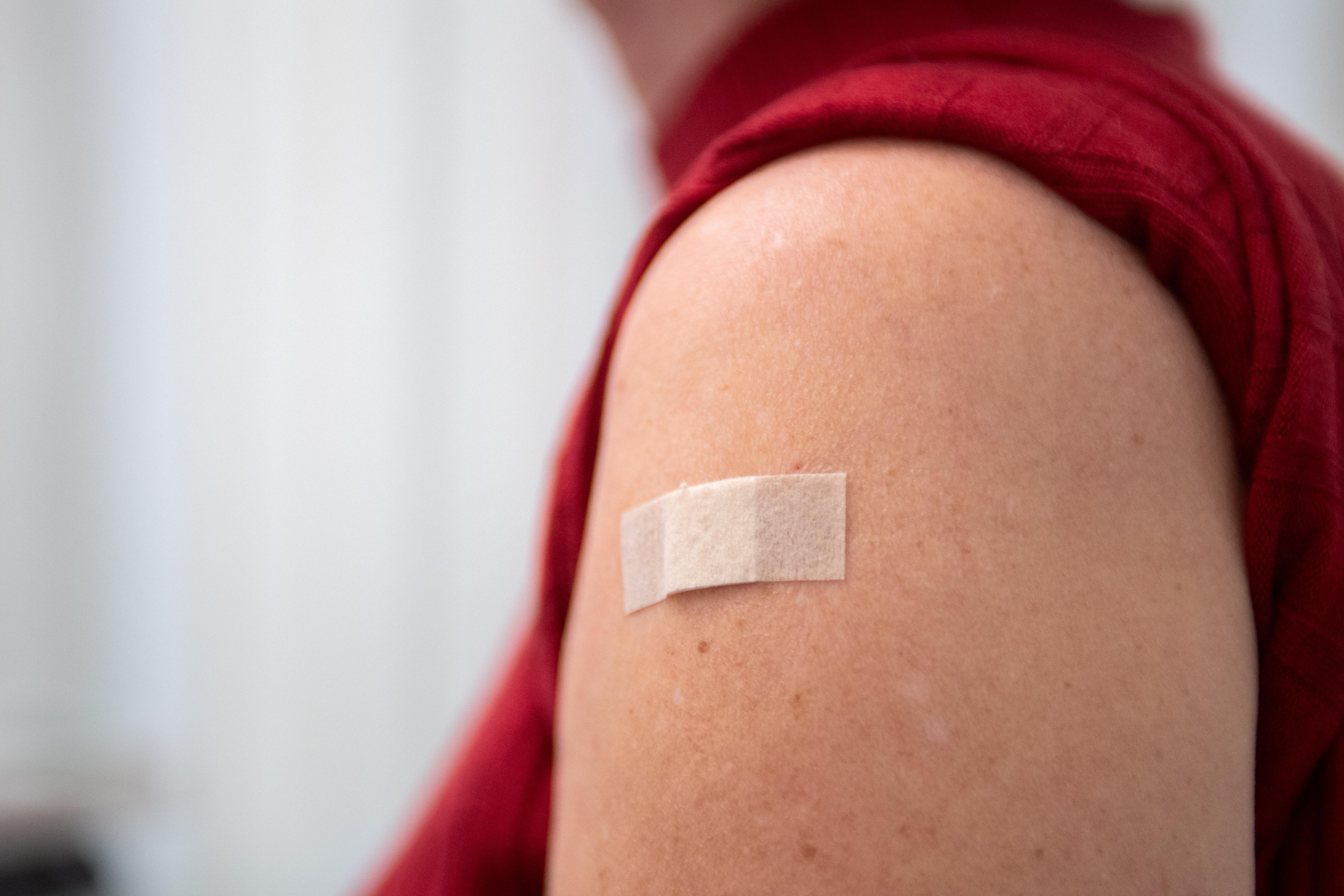Ein Pflaster klebt am 20.09.2023 in Berlin nach einer Grippeimpfung auf der Schulter einer Frau.