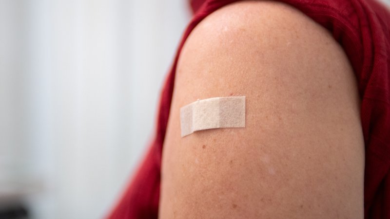 Ein Pflaster klebt am 20.09.2023 in Berlin nach einer Grippeimpfung auf der Schulter einer Frau.