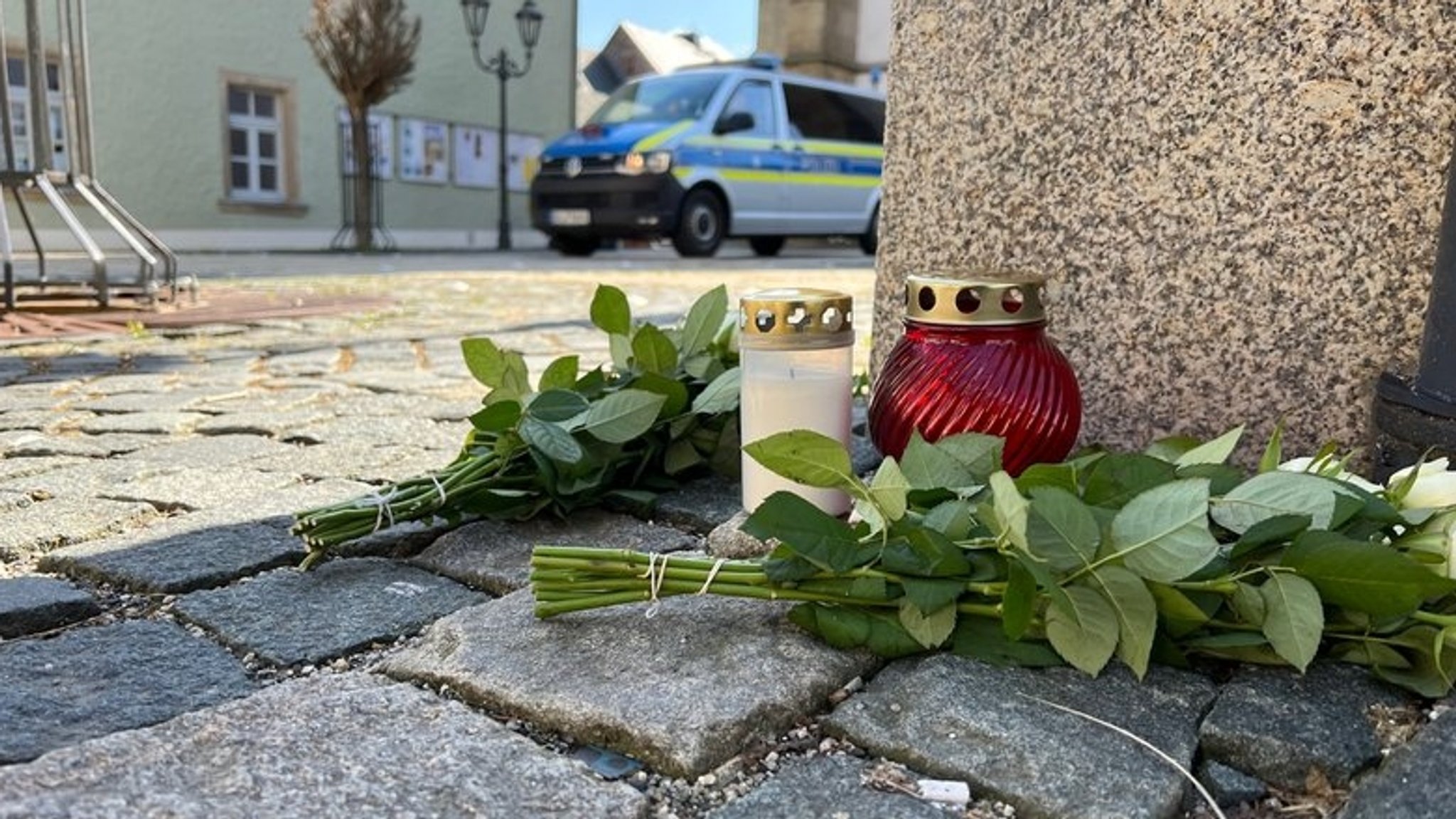 Blumen und Grabkerzen liegen auf dem Boden. 