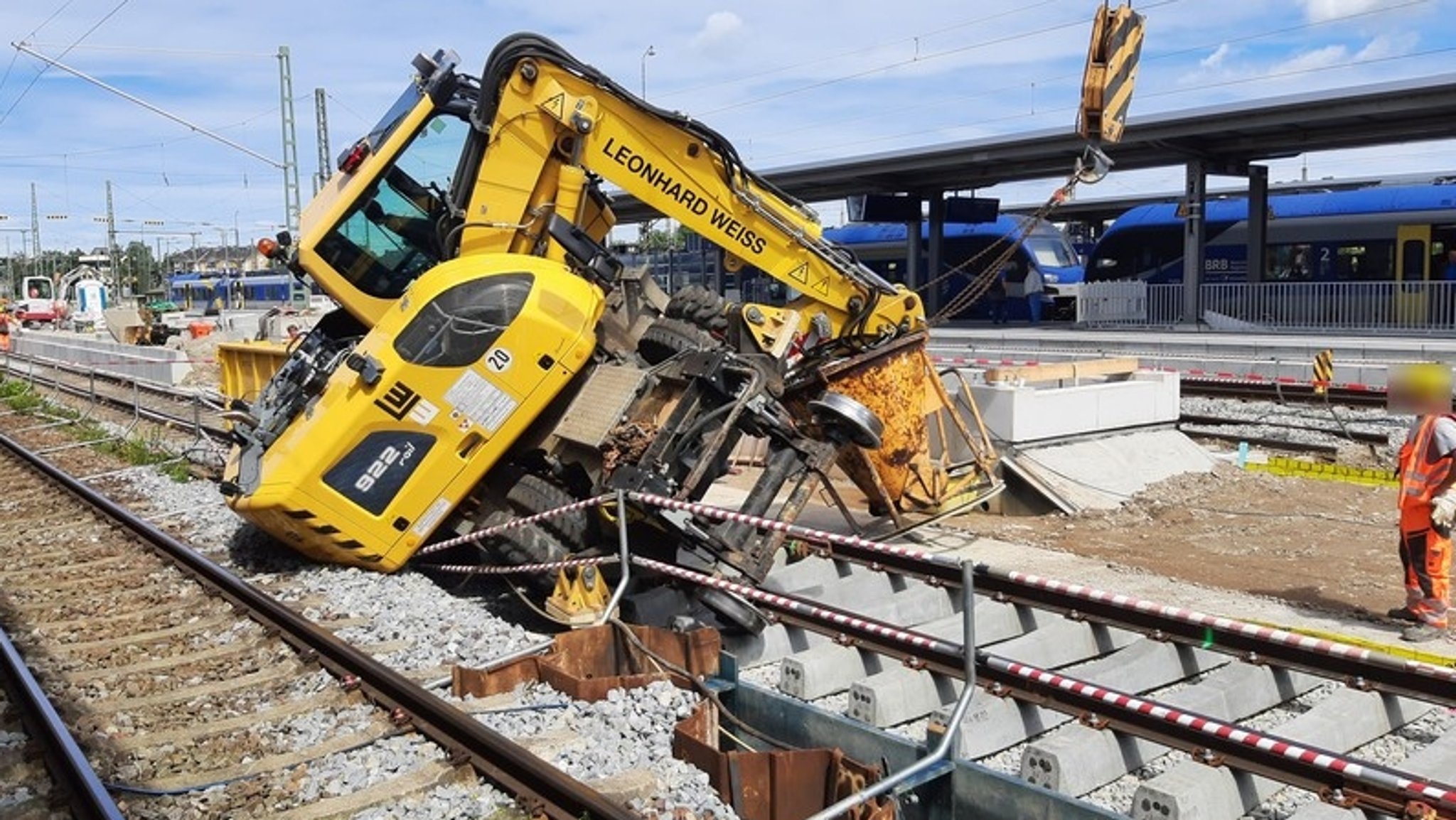 gelber Bagger kippt bei Bauarbeiten am Bahnhof Freilassing auf Gleis 