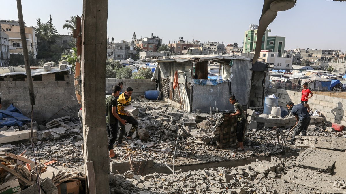 Palästinenser suchen nach brauchbaren Gegenständen in einem zerstörten Haus in Rafah.