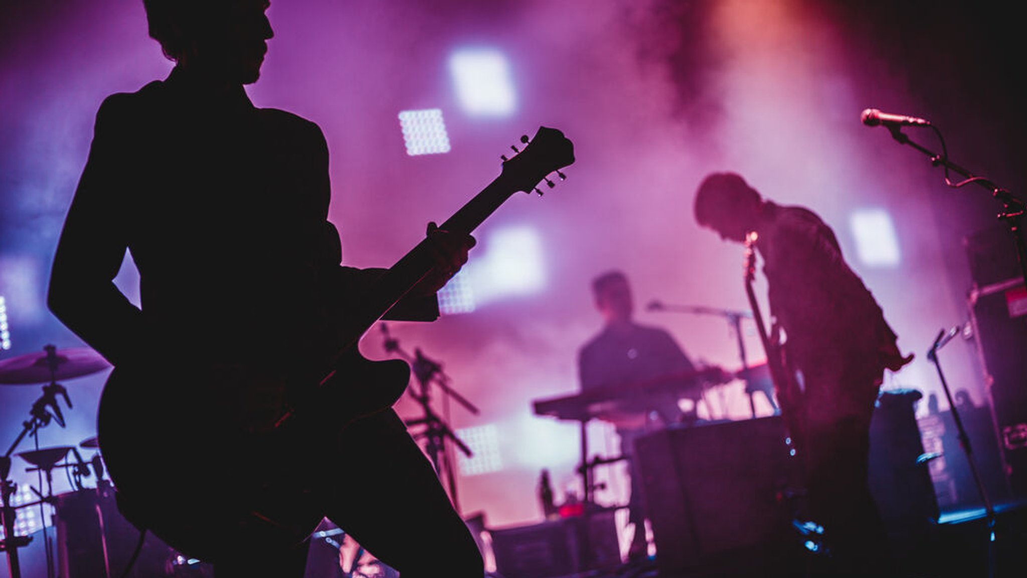 (Symbolbild) Silhouetten einer Musikband auf einer Konzertbühne.