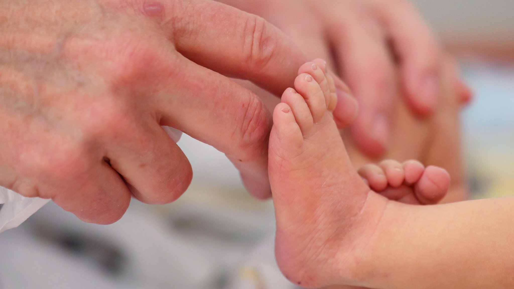 Eine Hand streichelt einen Babyfuß. | Bild: dpa-Bildfunk/Hendrik Schmidt Eine Hand streichelt einen Babyfuß.