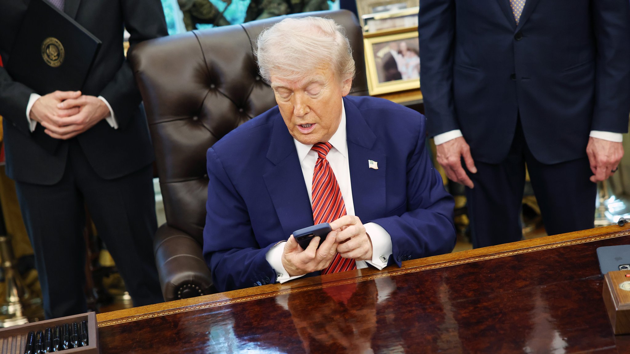 Der US-Präsident mit einem Handy am Schreibtisch