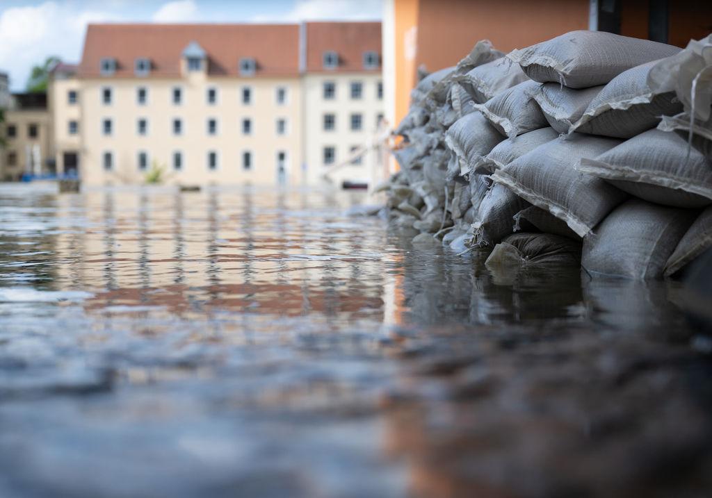04.06.2024, Bayern, Regensburg: Sandsäcke schützen in der Altstadt am Donauufer die Einfahrt von einer Garage. Seit Tagen kämpfen die Helfer in Bayern gegen die Flut und ihre Folgen. (zu dpa: «Hochwasser-Schutz in Deutschland: «Es braucht häufig den Weckruf»») Foto: Sven Hoppe/dpa +++ dpa-Bildfunk +++