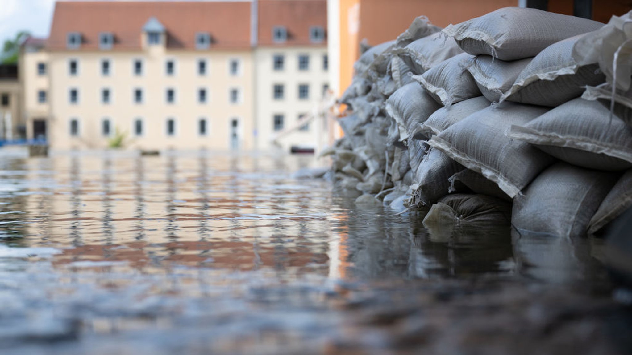 04.06.2024, Bayern, Regensburg: Sandsäcke schützen in der Altstadt am Donauufer die Einfahrt von einer Garage. Seit Tagen kämpfen die Helfer in Bayern gegen die Flut und ihre Folgen. (zu dpa: «Hochwasser-Schutz in Deutschland: «Es braucht häufig den Weckruf»») Foto: Sven Hoppe/dpa +++ dpa-Bildfunk +++