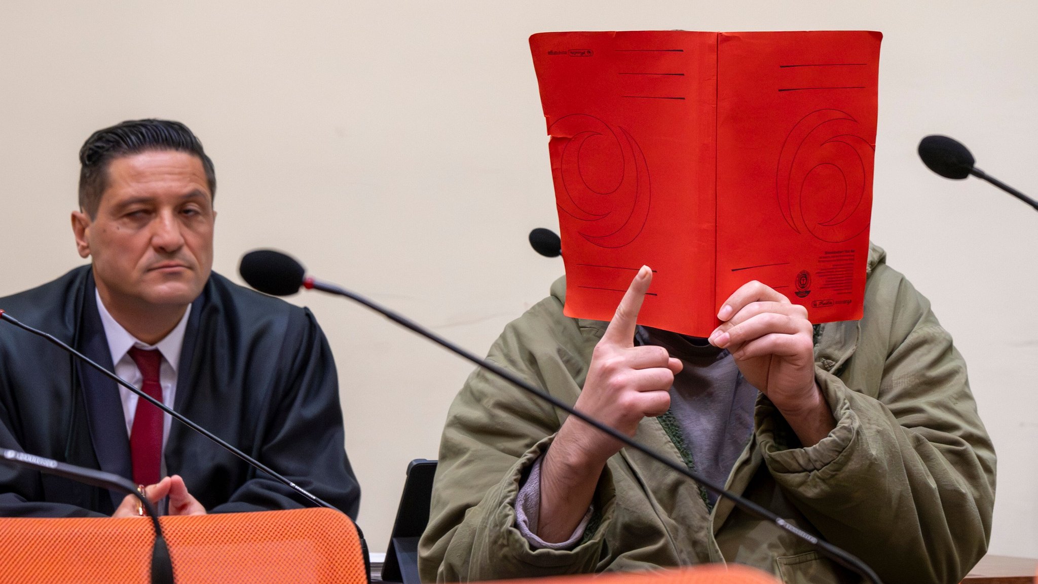 Vor den Kameras der Journalisten streckt der Angeklagte den rechten Zeigefinger nach oben - im Islam ein Symbol für den monotheistischen Glauben.